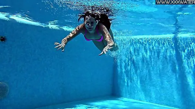 Babe in a pink bikini happily strips in the pool