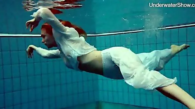 Elegant redhead goes swimming in her sexy clothes