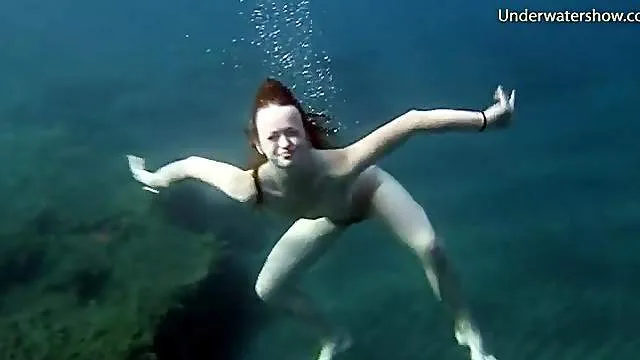 Naked redheaded beauty swims in the ocean