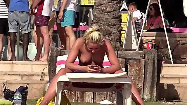 Cute tanned girl reading topless on a beach