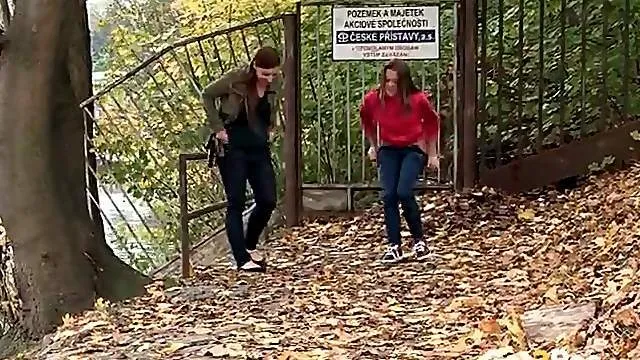 Two cute girls pee in the leaves outdoors
