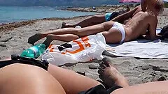 Girl gives a head to her friend on the public beach