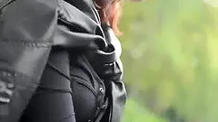 Prostitute in leather clothes smokes while waiting for clients