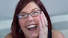 Mature redhead in a pair of sexy glasses gives a blowjob