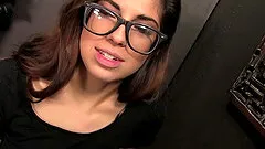 Tattooed brunette with glasses sucking a stranger's cock through a glory hole