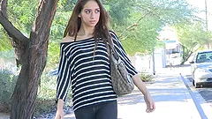 Slim brunette with an engaing smile takes off clothes in a park