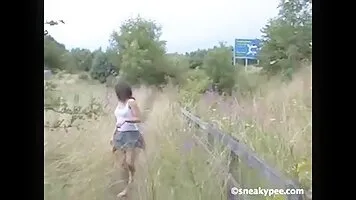 Swarthy girl pee in the grass