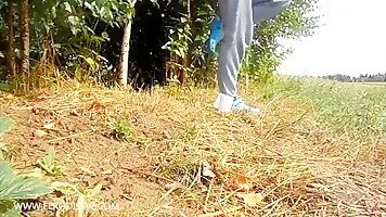 Girl in a blue shirt scat near bushes