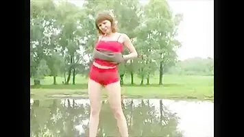 Girl in red pissing near pond